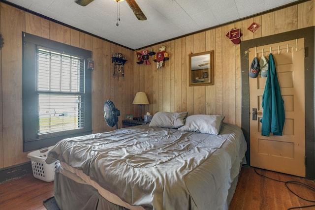 bedroom with wood-type flooring, ceiling fan, and wooden walls