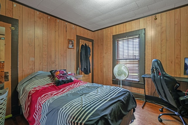 bedroom with wood walls and wood finished floors