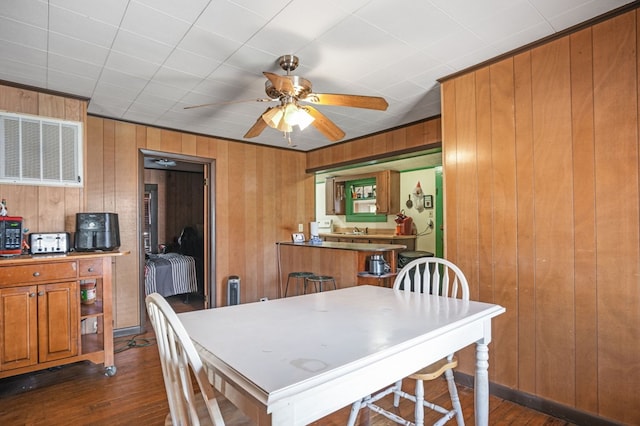 dining space with wooden walls, visible vents, dark wood-type flooring, and ceiling fan