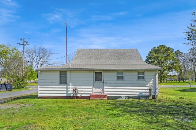 view of front of house featuring entry steps, roof with shingles, and a front lawn