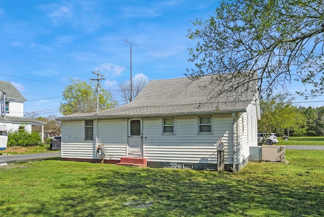view of front of property featuring a shingled roof, a front lawn, and entry steps