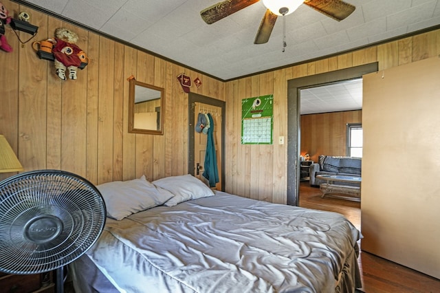 bedroom with wood finished floors, wood walls, and a ceiling fan