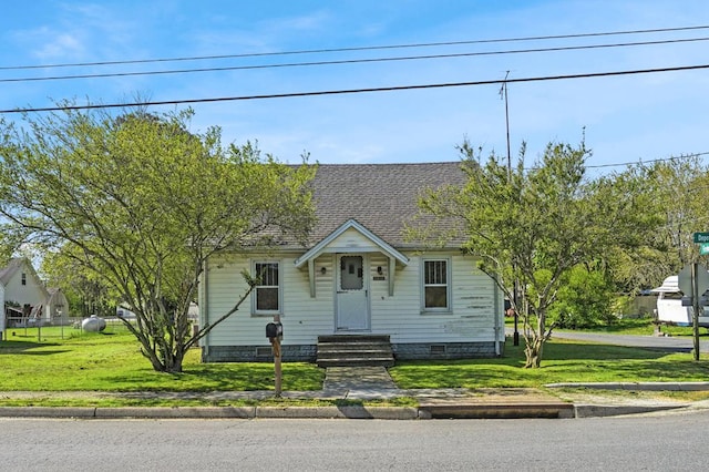 view of front facade featuring fence, a shingled roof, and a front yard