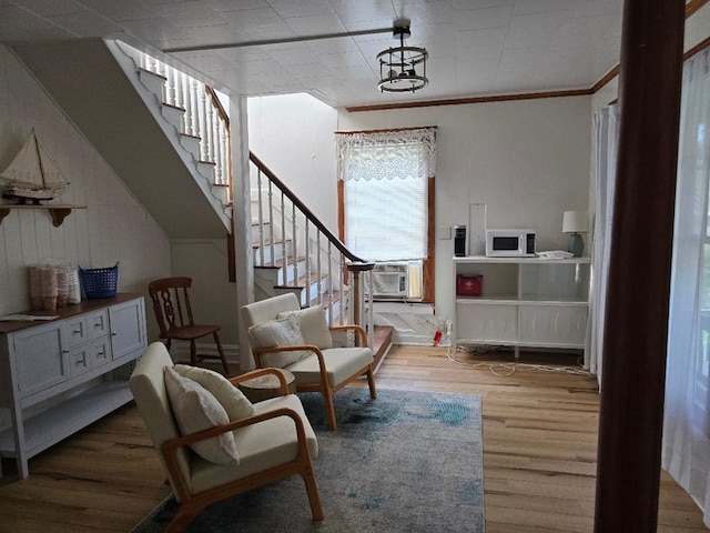 living area with cooling unit, light wood-type flooring, and crown molding