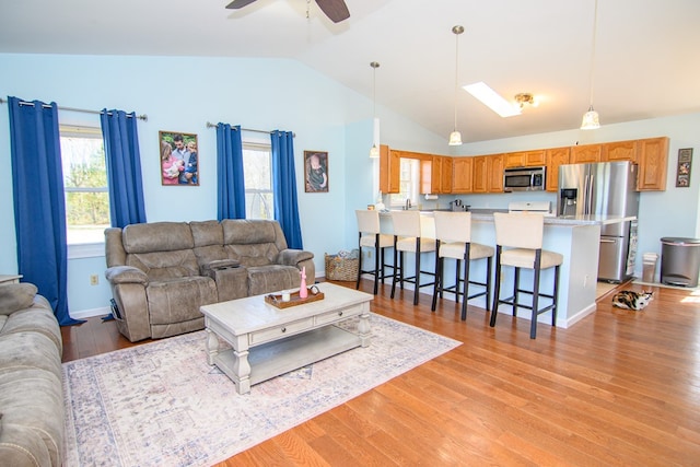 6545 Occohannock Neck Rd, Exmore, VA 23350 - living area featuring vaulted ceiling with skylight, baseboards, light wood-type flooring, and ceiling fan