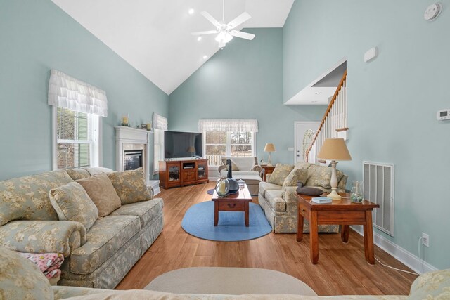 living room featuring light hardwood / wood-style flooring, high vaulted ceiling, and ceiling fan