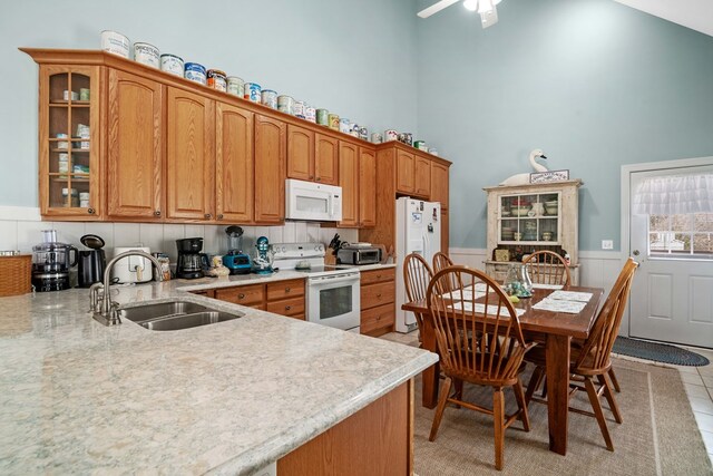 kitchen featuring ceiling fan, sink, a high ceiling, white appliances, and light tile patterned flooring