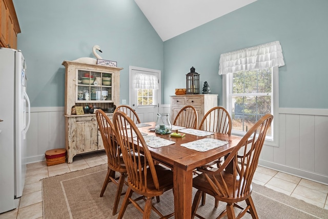 dining space with light tile patterned flooring and vaulted ceiling