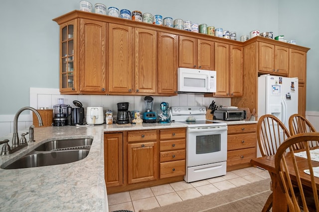 kitchen with sink, tasteful backsplash, light stone counters, white appliances, and light tile patterned floors