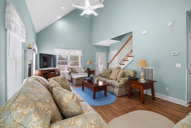 living room with hardwood / wood-style flooring, ceiling fan, and high vaulted ceiling