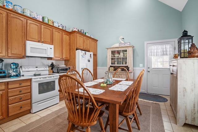 kitchen with vaulted ceiling, light tile patterned floors, and white appliances