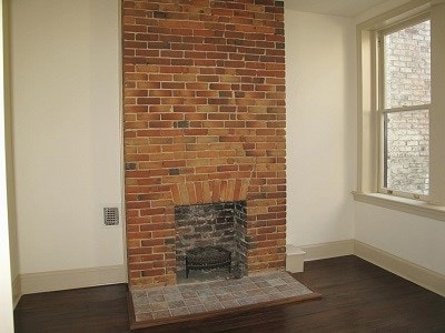 unfurnished living room with dark wood-style flooring, a fireplace, and baseboards