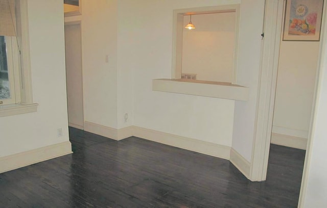 spare room with dark wood-style flooring and baseboards