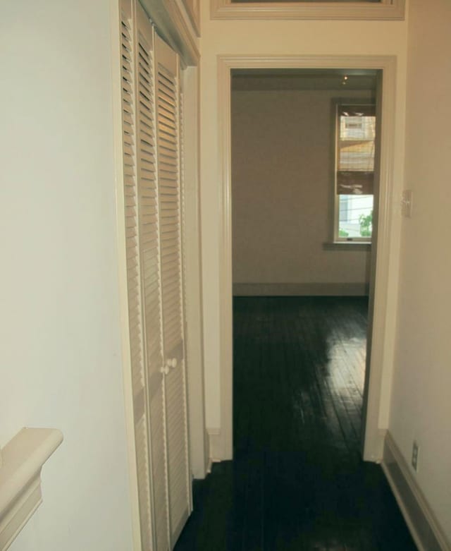 hallway featuring dark wood-style flooring and baseboards