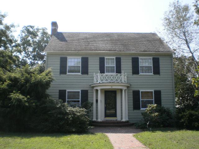 view of front of property with a chimney, a front yard, and a balcony