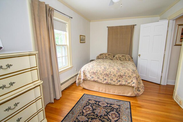 86 Market St, Onancock, VA 23417 - bedroom with baseboard heating, crown molding, light wood-style floors, ceiling fan, and baseboards