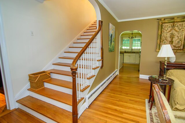 86 Market St, Onancock, VA 23417 - staircase featuring a baseboard radiator, arched walkways, wood finished floors, crown molding, and baseboards