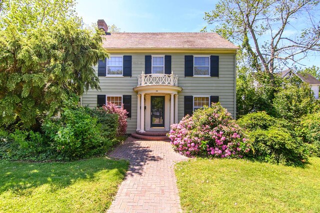 86 Market St, Onancock, VA 23417 - view of front of home with a front yard, a chimney, and a balcony