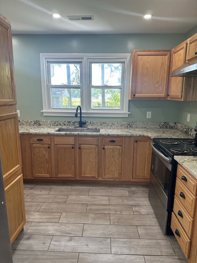 kitchen with a sink, electric stove, wood tiled floor, under cabinet range hood, and visible vents