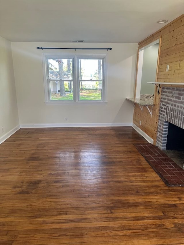 unfurnished living room with baseboards, a fireplace, visible vents, and hardwood / wood-style floors