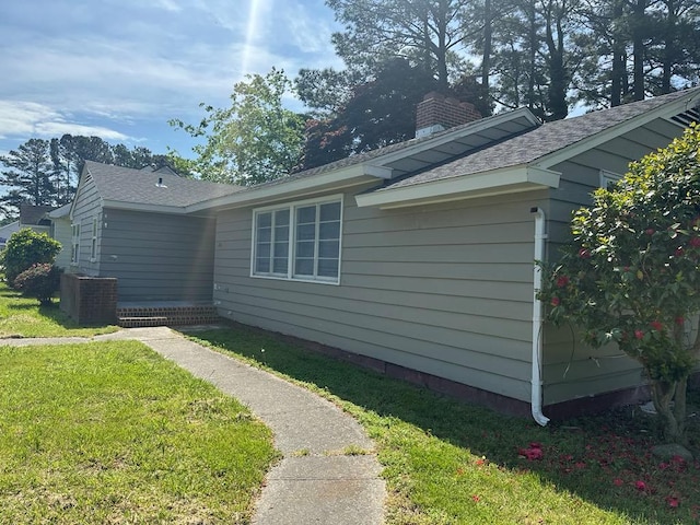 view of home's exterior with a yard, cooling unit, a chimney, and roof with shingles