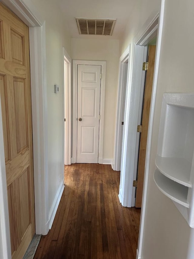 hallway with baseboards, visible vents, and dark wood-style floors
