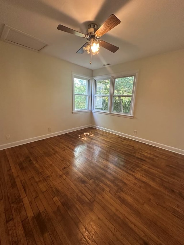 unfurnished room featuring baseboards, attic access, and dark wood finished floors