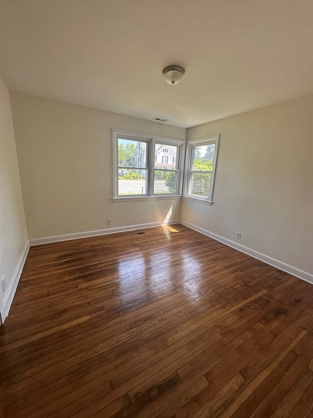 empty room with baseboards, dark wood finished floors, and visible vents