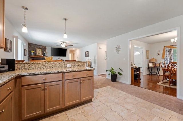 kitchen with light stone countertops, decorative light fixtures, ceiling fan, and light colored carpet