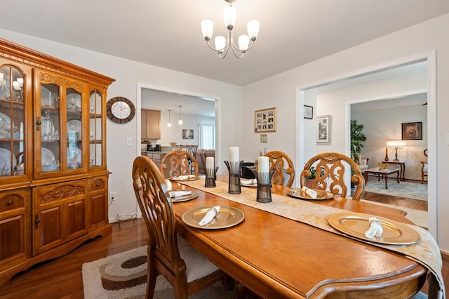 dining space with dark wood-type flooring and an inviting chandelier