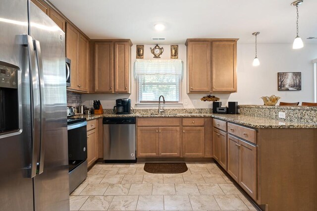 kitchen with hanging light fixtures, sink, light stone countertops, appliances with stainless steel finishes, and kitchen peninsula