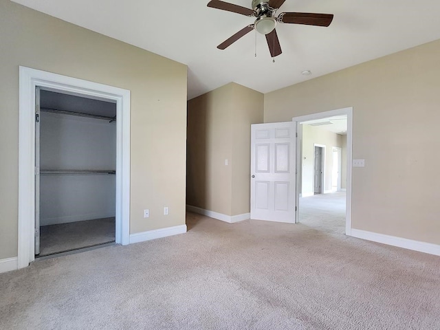 unfurnished bedroom with ceiling fan, a closet, light carpet, and a walk in closet