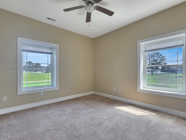 spare room featuring a wealth of natural light, carpet floors, and ceiling fan