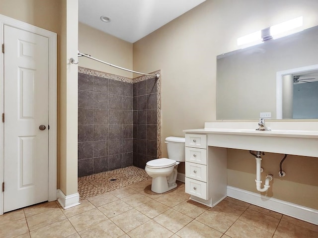 bathroom with tile patterned flooring, a tile shower, and toilet