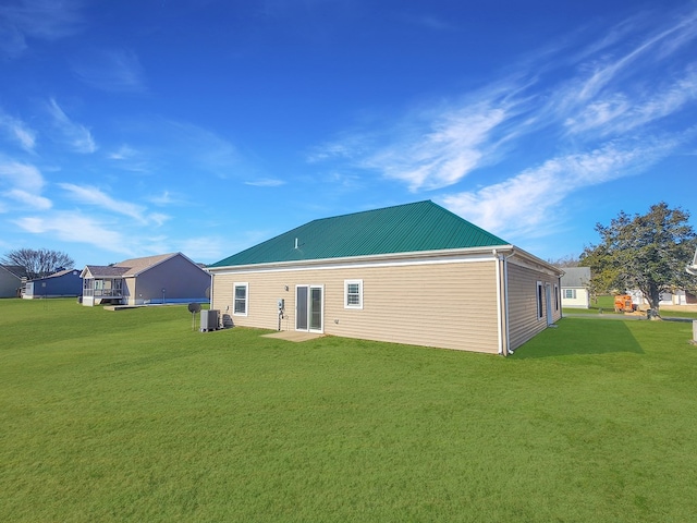 rear view of property with cooling unit and a lawn