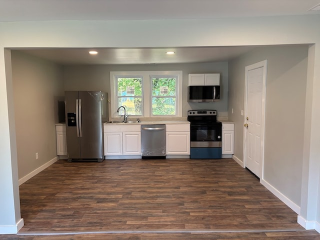 kitchen with stainless steel appliances, white cabinetry, dark wood-type flooring, and sink