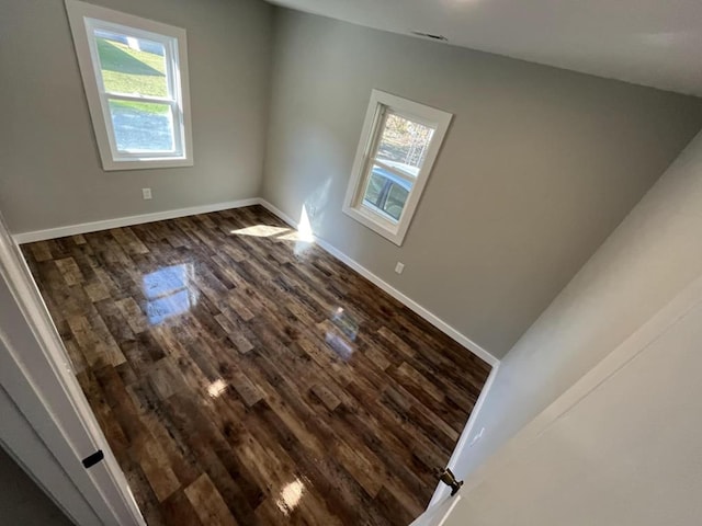 empty room with dark hardwood / wood-style floors and a wealth of natural light