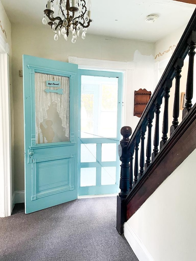 carpeted entryway with an inviting chandelier