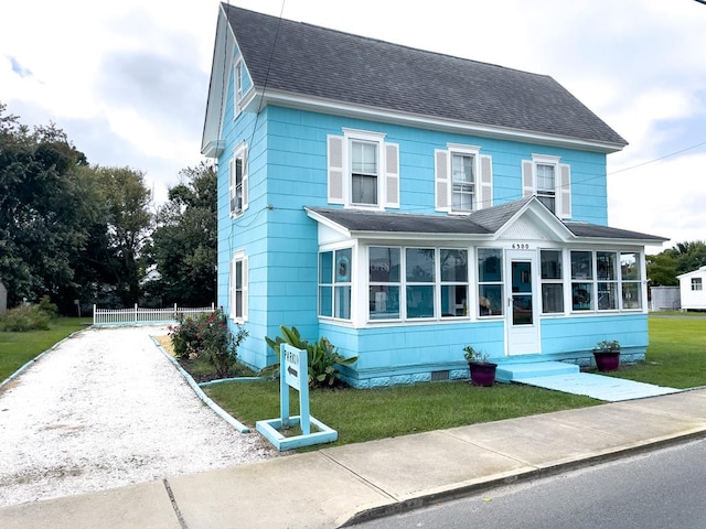 view of front of house featuring a sunroom and a front yard