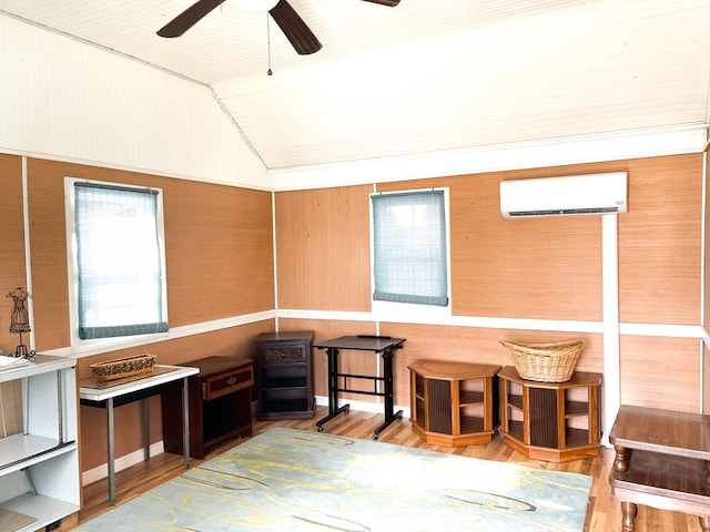 interior space with wood-type flooring, a wall unit AC, and vaulted ceiling