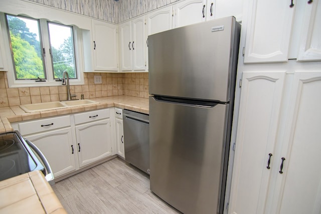 kitchen with tile countertops, white cabinetry, sink, and appliances with stainless steel finishes