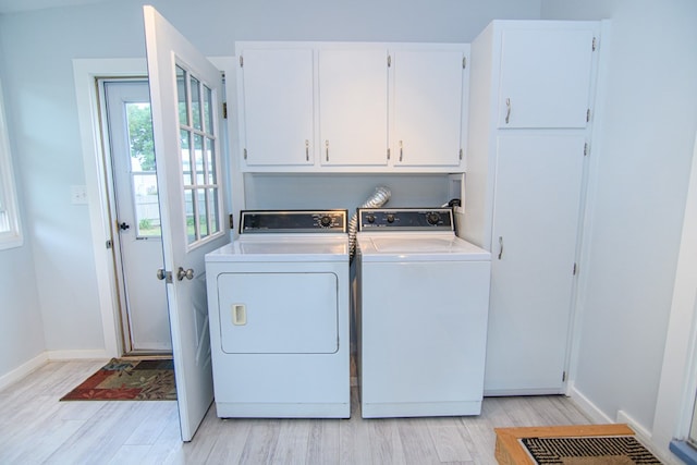 laundry room featuring washer and dryer, cabinets, and light hardwood / wood-style flooring