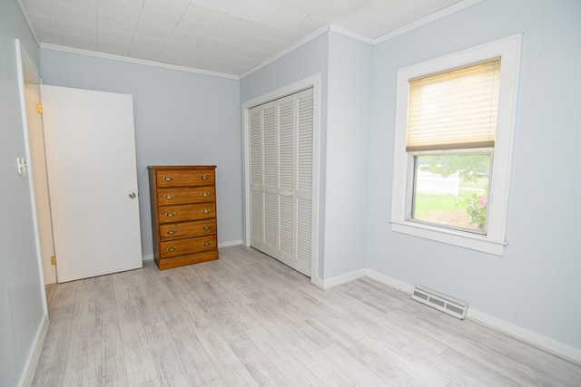 unfurnished bedroom featuring light hardwood / wood-style floors, a closet, and crown molding