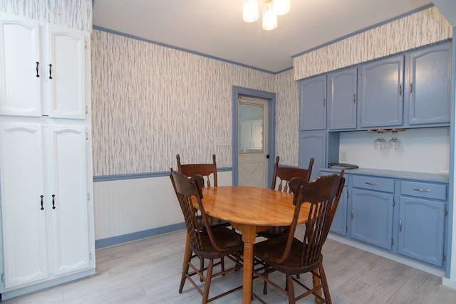 dining area with ornamental molding and light hardwood / wood-style flooring