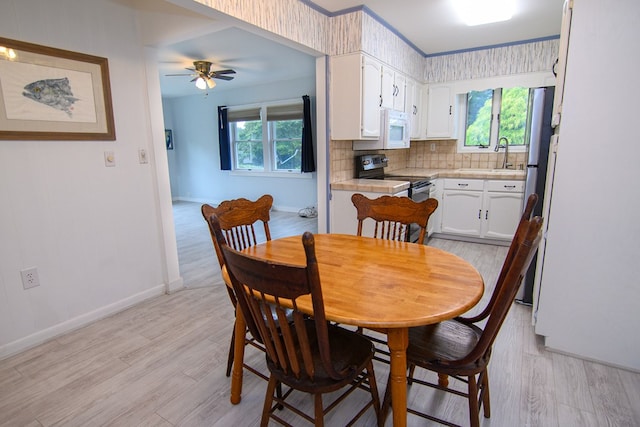 dining room featuring a wealth of natural light, light hardwood / wood-style flooring, ceiling fan, and sink