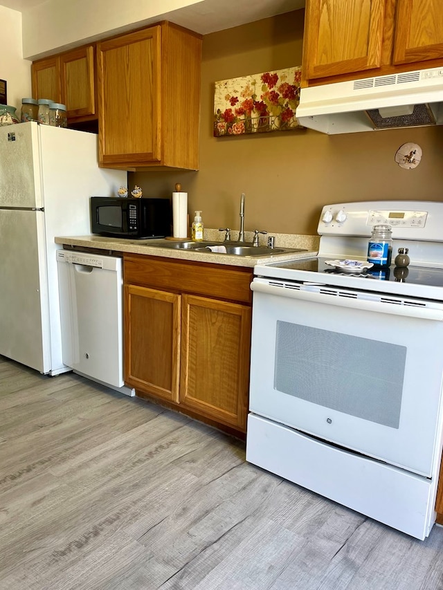 kitchen with white appliances, sink, and light hardwood / wood-style flooring