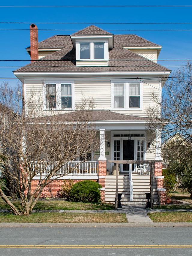 traditional style home with covered porch and roof with shingles