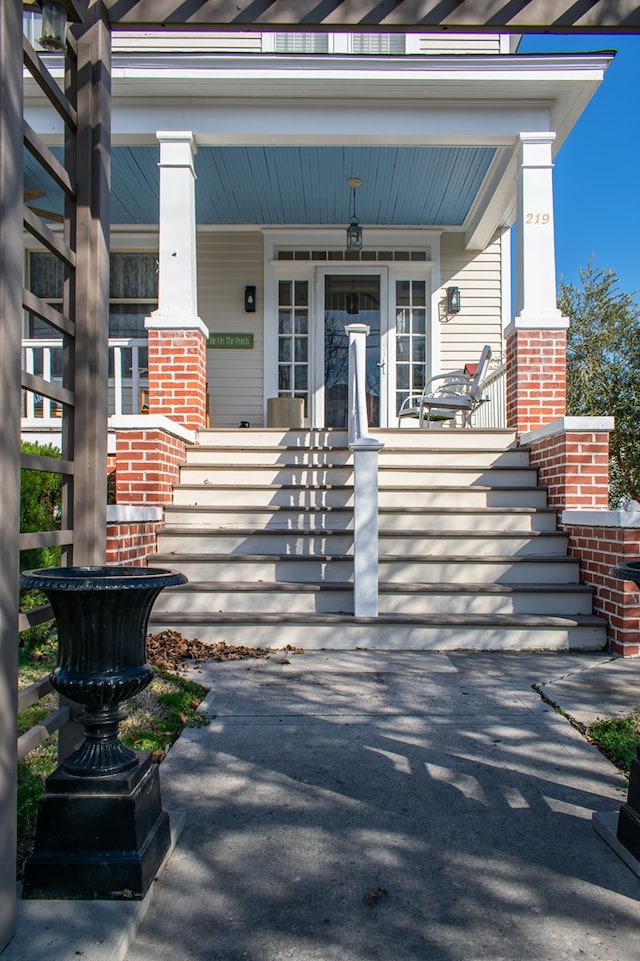 entrance to property featuring covered porch and brick siding