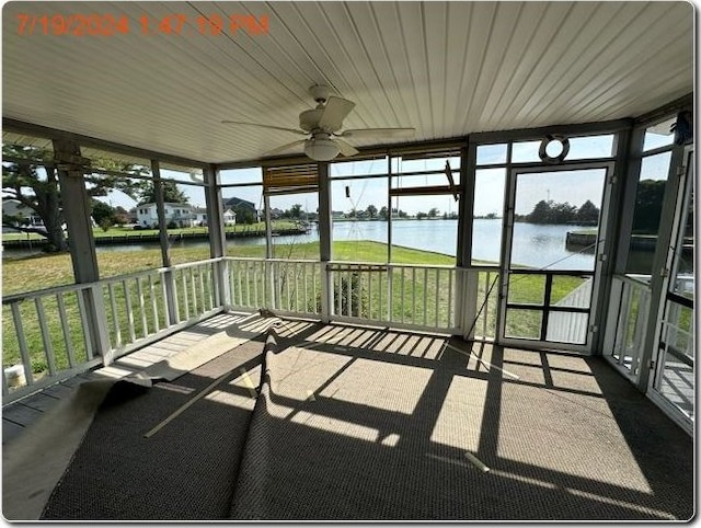 unfurnished sunroom with ceiling fan and a water view