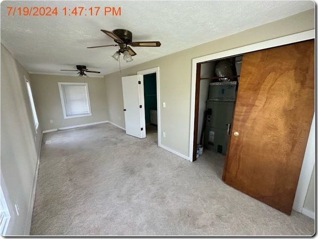 unfurnished bedroom featuring a textured ceiling, light colored carpet, and ceiling fan